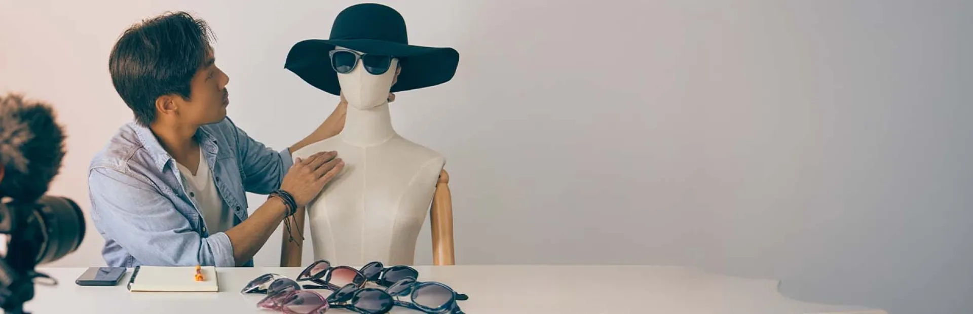 Blogueur asiatique mettant des lunettes de mode sur le visage des mannequins et enregistrant une vidéo.