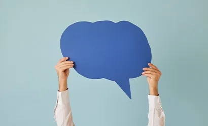 Deux mains tenant une grande bulle de dialogue bleue découpée sur un fond bleu clair.